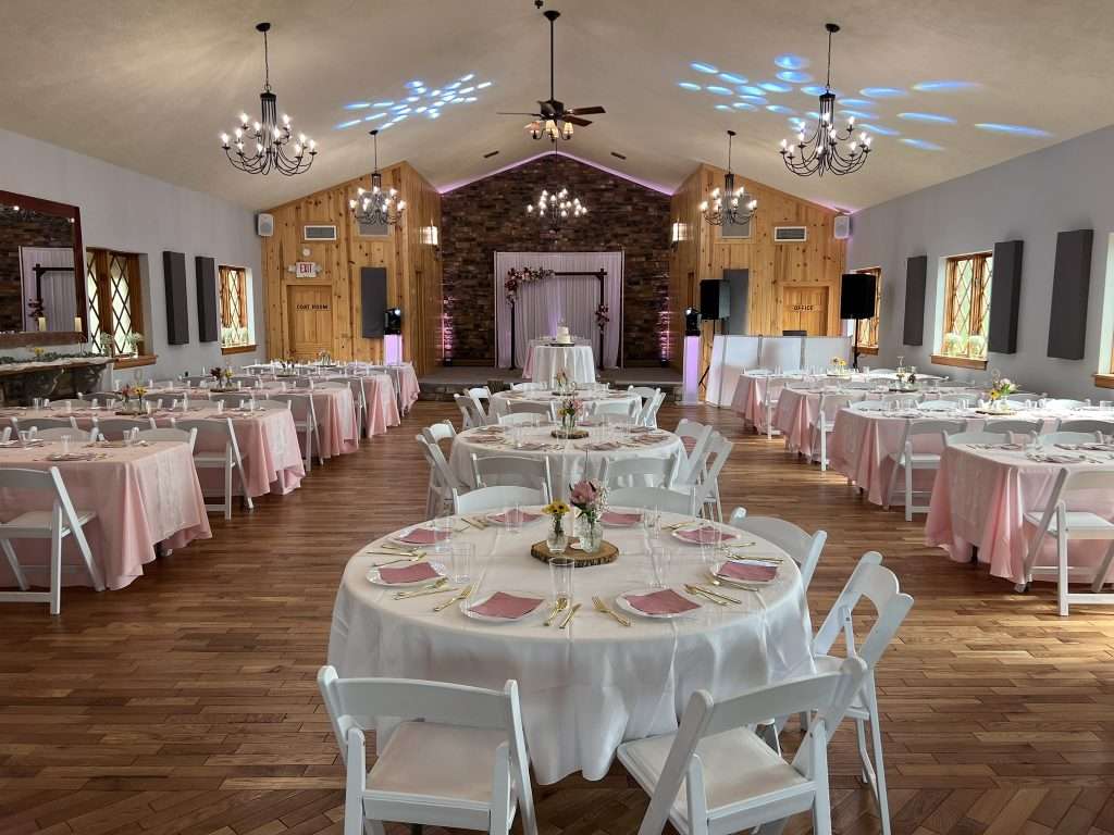 Sanctuary at The Hidden Abbey decorated for a wedding reception with pink linens, round and banquet tables, and wood floors. The Hidden Abbey is located near Carrollton, Ohio.