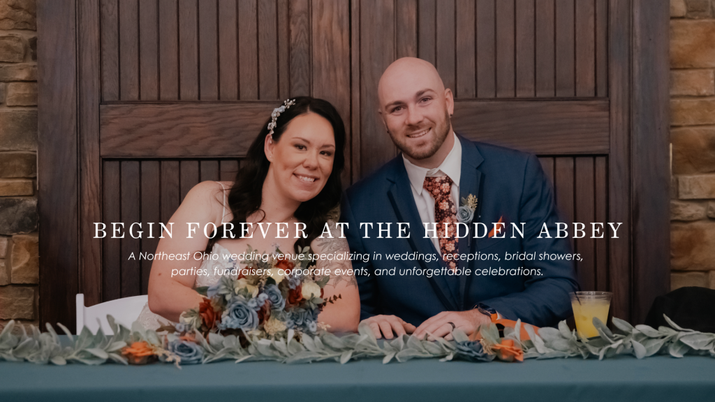 Bride and groom seated at their beautifully decorated head table during their wedding reception at The Hidden Abbey in Northeast Ohio.